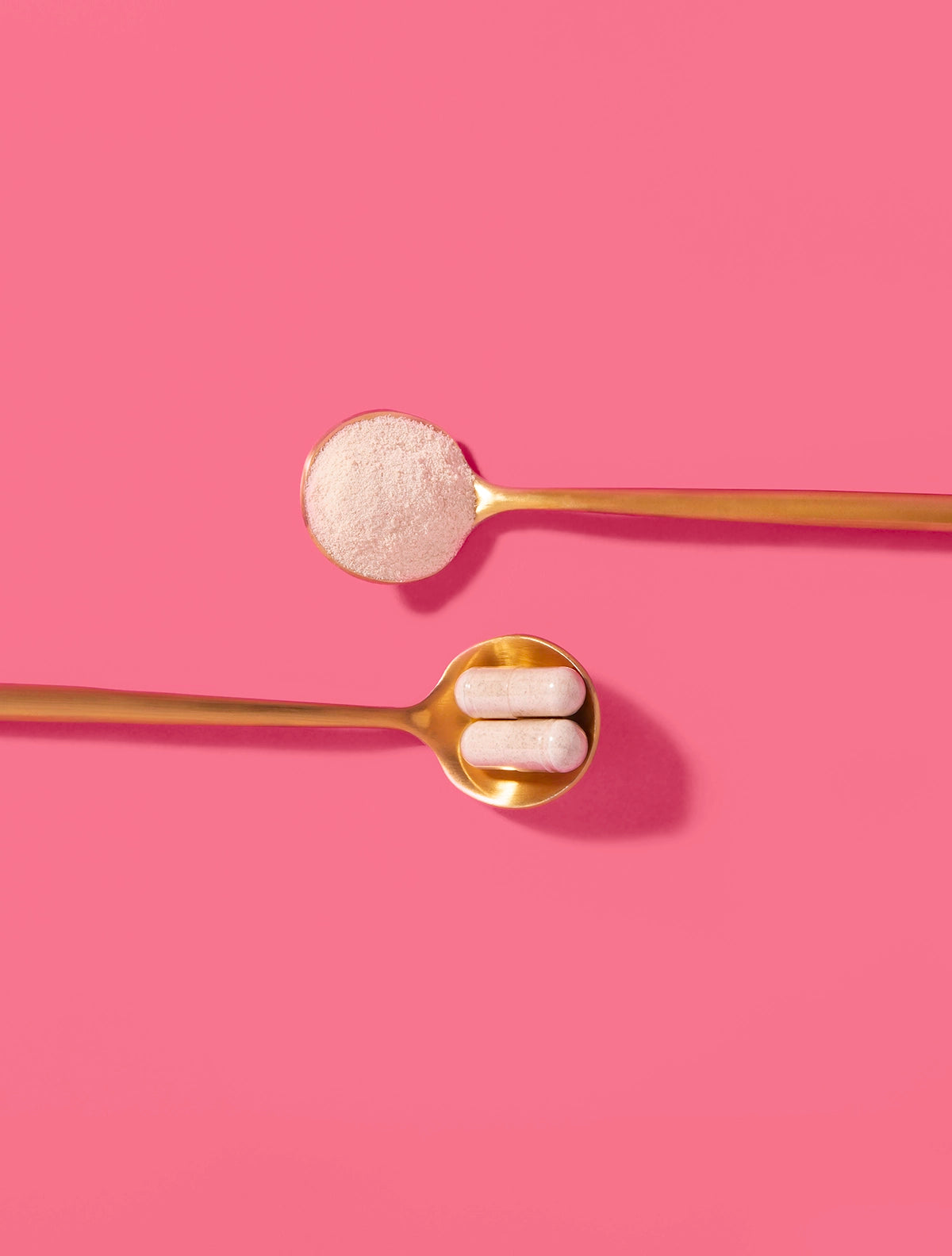 A scoop of Renew+ Marine collagen powder on a gold spoon, alongside 2 Hair Skin Nails capsules on another gold spoon on a pink background